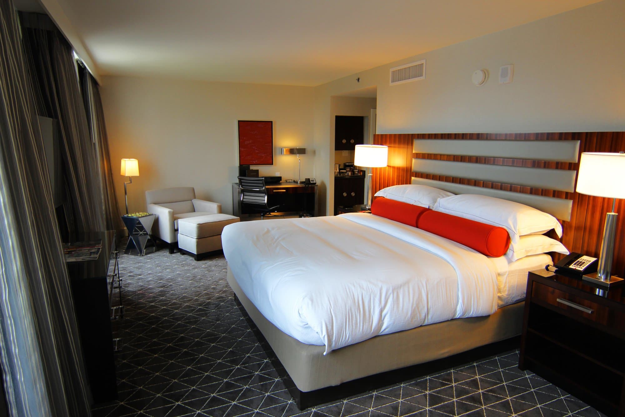 Hotel room with a bed made with white sheets and a geometric patterned carpet.