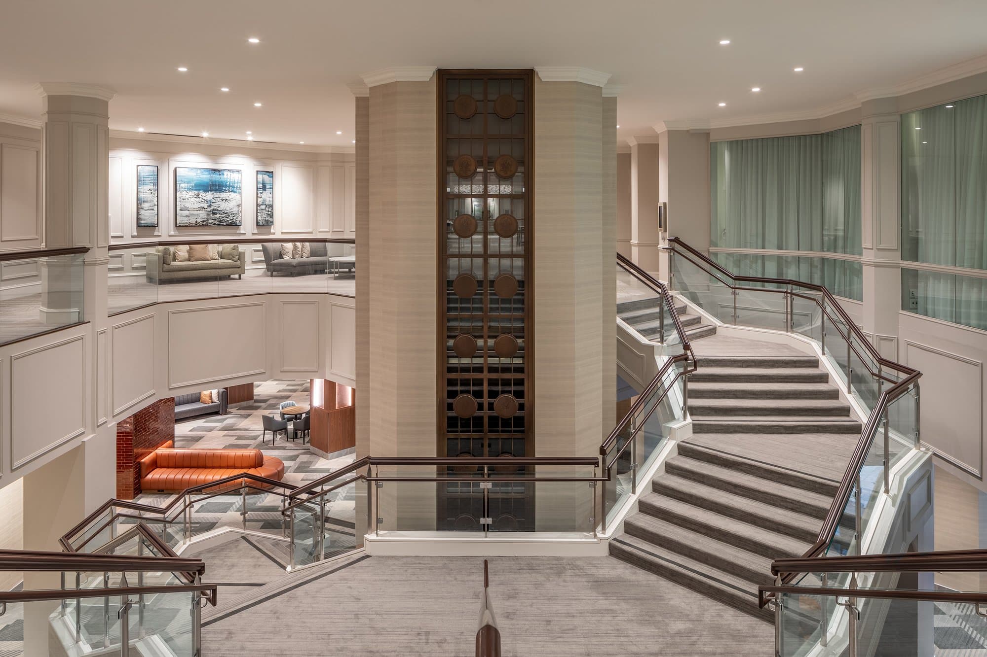A hotel lobby with a staircase and glass railings.