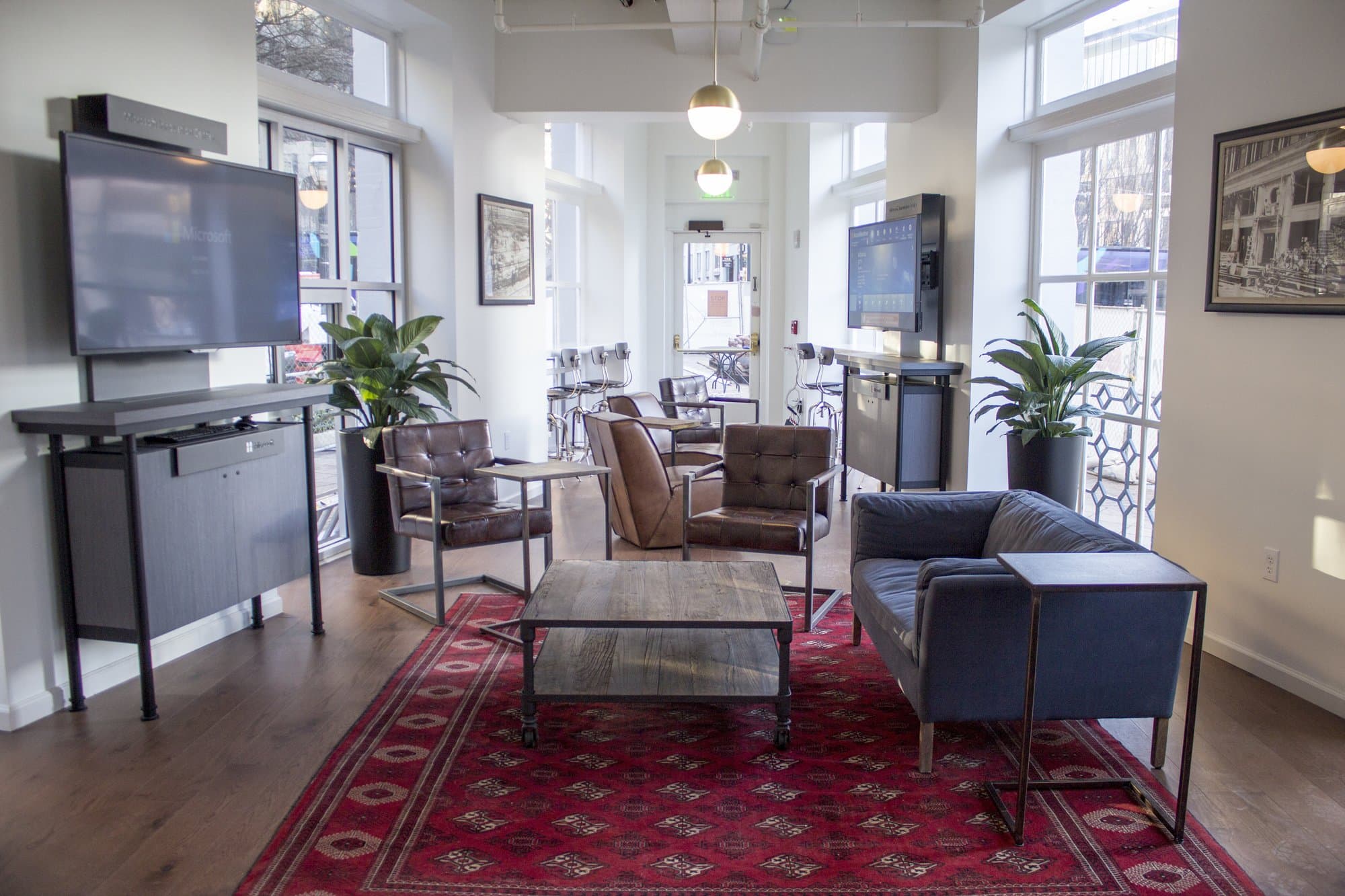 Casual seating area with sofas, chairs, and a TV on the wall.