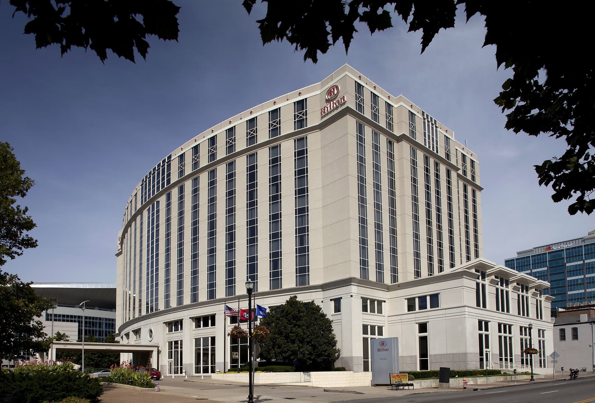 White exterior mid-rise building with the Hilton logo at the top corner.