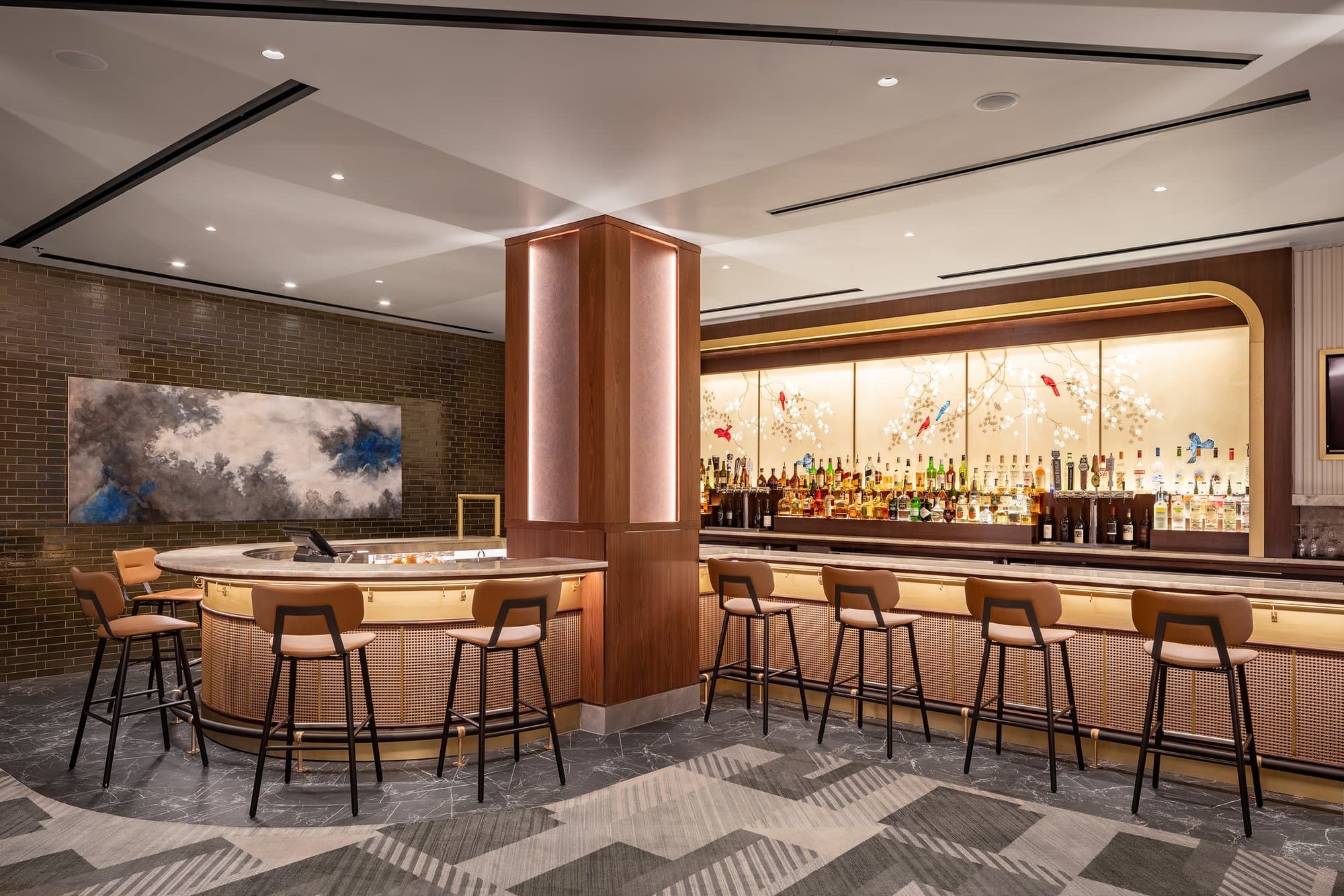 A bar with stools and a large painting.