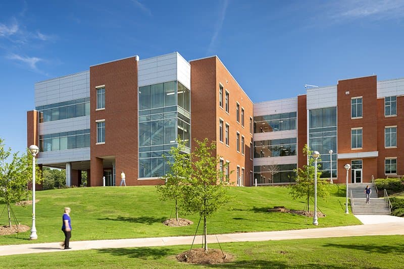 Exterior view of academic building with grassy area and sidewalks.