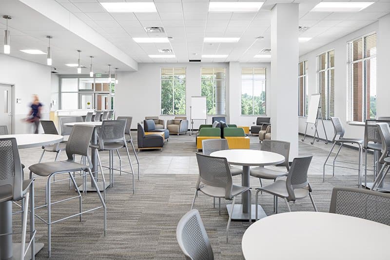 Student seating area with tables, chairs, and sofas.